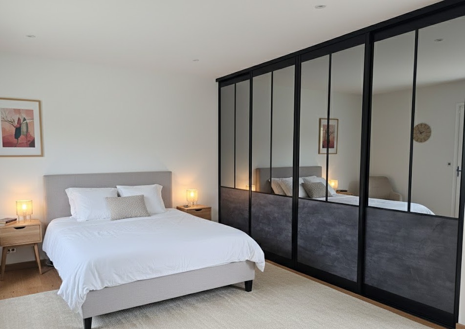 Dressing sur mesure avec portes coulissantes miroir et verrière noire dans une chambre moderne
